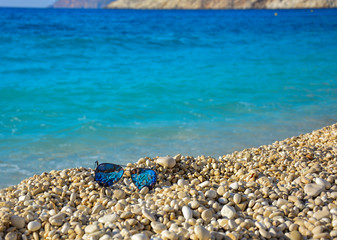 Fototapeta na wymiar Gafas de sol azules en la playa de Grecia