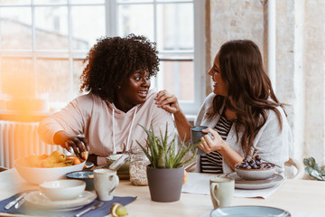 Zwei junge Frauen unterhalten sich beim Frühstück in einer WG