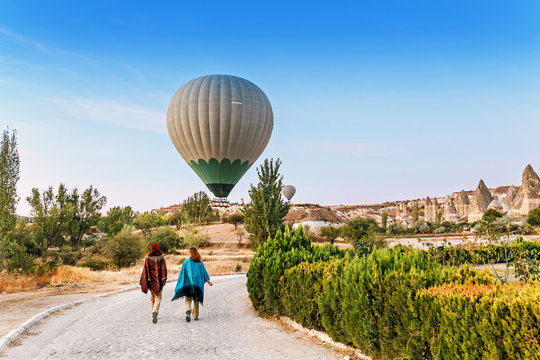 Couple of friends travelers enjoying valley view with wonderful balloons flight over Cappadocia valley in Turkey