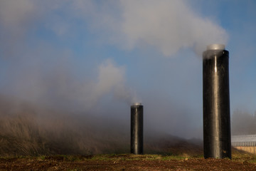 Pipes Emitting Steam at Geothermal Plant with Blue Sky Background