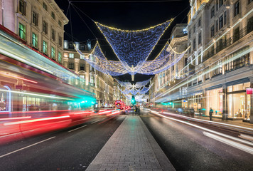 Die Einkaufsstraße Regent Street in London bei Nacht mit Weihnachtsbeleuchtung und vorbeifahrendem Bus Verkehr