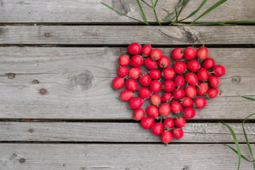 Red heart of hawthorn berries on a wooden background