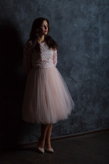 Naklejka premium Young girl in a pink dress. Dark blue background.