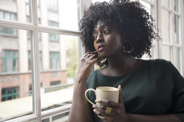 joven mujer negra toma café en la ventana