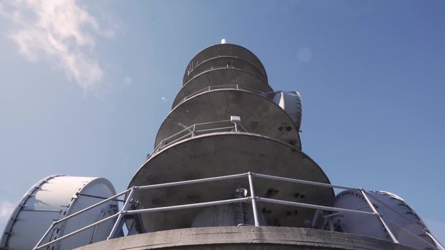 4K Looking Up at Large Antenna Radio Tower With Sun Flare, Pan Down Slide Back
