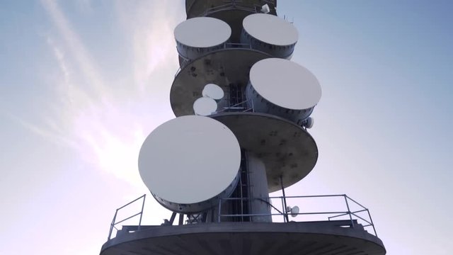 4K Looking Up at Large Antenna Radio Tower With Bright Sun, Pan Up