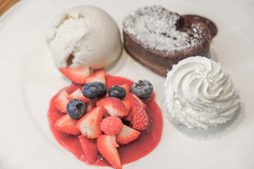 Chocolate Lava Cake with Vanilla Ice Cream, Whip Cream and Mixed Fruit on the white plate