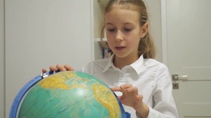 Little girl is studying the globe at home. - Powered by Adobe