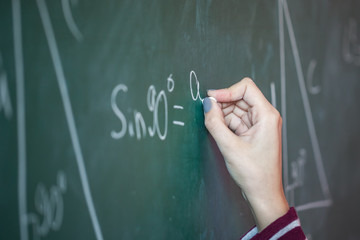 girl with chalk in her hand solves a mathematical problem on the blackboard