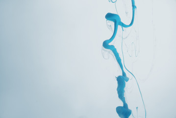 Ink swirl in water. droplets of blue ink in water close-up. Abstract background. Soft focus.