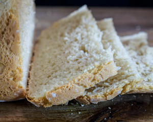 Closeup on sliced, machine-made white flour bread on wooden table