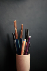 Obraz premium pens pencils brushes in a stand black chalkboard class crafts