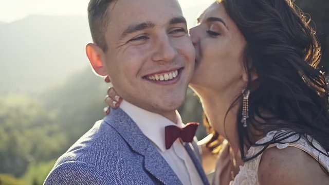 Crazy wedding lovers are newly married, passionately and funnyly cherished on the background of the tangled rays of the sun that is between the rocky mountains.