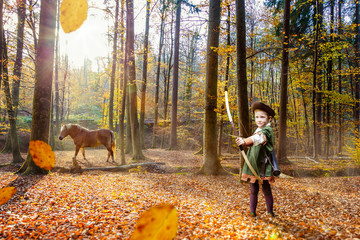 Junge spielt Robin Hood im Herbstwald