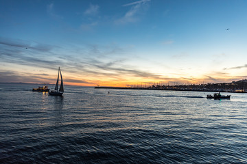 sailing boats heading back to harbor at sunset time while the clouds look spectacular in the sky