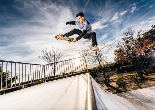 Young skater making a jump on Skatepark during sunset