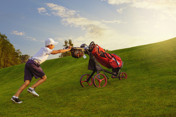Boy golf player walking with bag on fairway