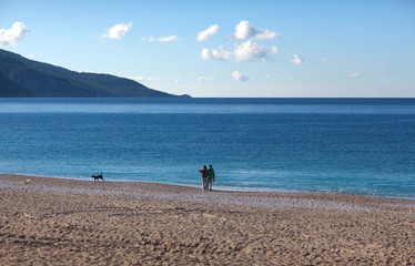 Tourists walking with dogs on the Belcekiz beach in Oludeniz, Turkey