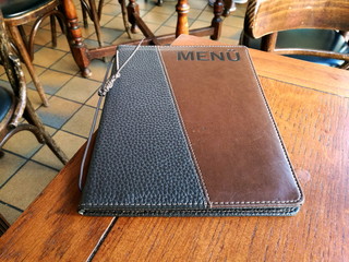 Ledereinband in Schwarz und Braun einer Speisekarte auf dem Holztisch eines Café und Bistro im...