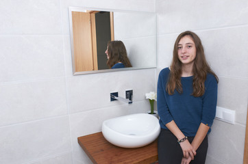 Beautiful teenage girl standing in a design bathroom.