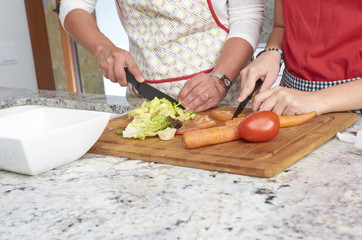 Mother and her teenage daughter are cooking together in the kitchen, prepare a salad. Vegan Family.