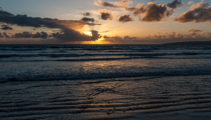 Fototapeta na wymiar Beach sunset and gentile ocean waves in golden light