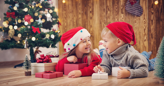 Boy and girl lying on the floor with presents near christmas tree