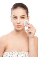 Young girl cares for face skin relaxation. Beautiful young brunette woman with clean perfect fresh skin using cotton pad. Youth and skin care concept. Isolated on a white.