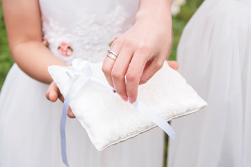 Close-up hand bridesmaid in white dress takes with pads rings.