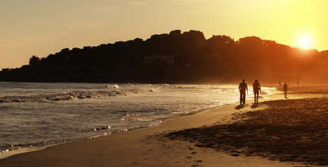 Silhouette of couple walking on the beach at sunset