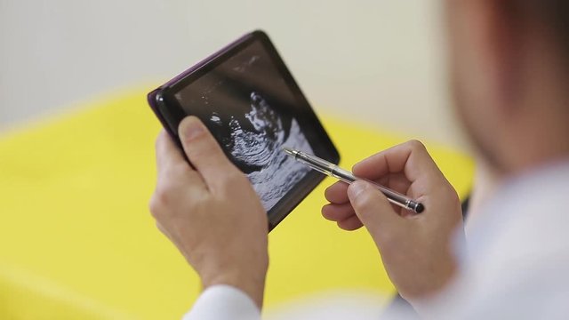 doctor shows a pregnant woman a picture of an ultrasound on a tablet