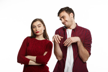 Horizontal portrait of irritated angry young female dressed in cozy sweater keeping arms crossed,...