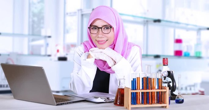 Young muslim scientist smiling in the lab with a laptop computer and test tube on the table, shot in 4k resolution