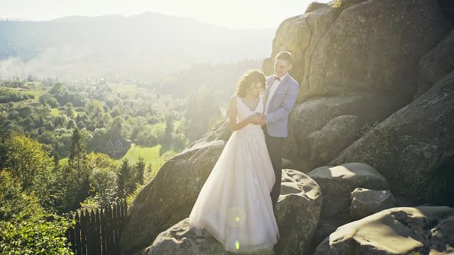 Beautifull wedding couple kissing and embracing near the shore of a mountain river with stones