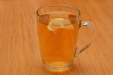Transparent glass cup with tea and a slice of lemon is on the table