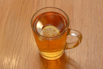 Transparent glass cup with tea and a slice of lemon is on the table. The view from the top