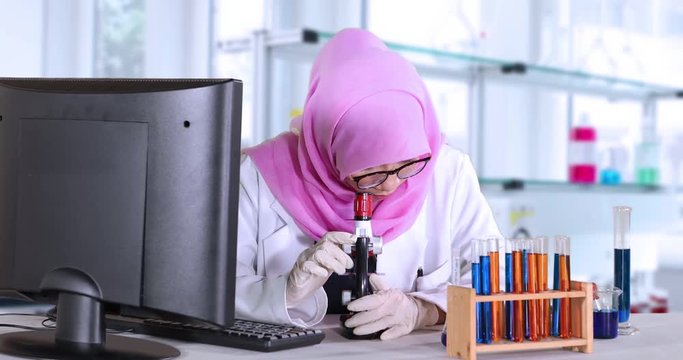 Muslim scientist working with a computer, microscope, and test tube in the laboratory. Shot in 4k resolution