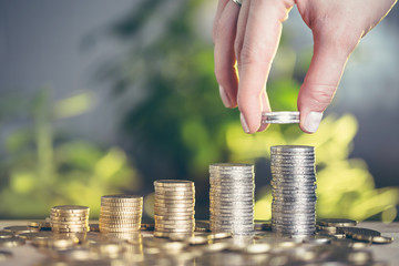 Money saving concept. A woman's hand puts money on a pile of money. Shallow depth of field.