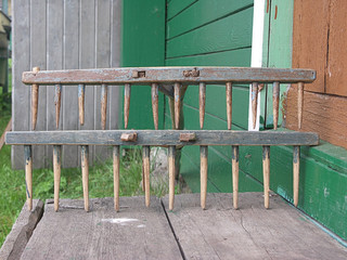 old wooden rake on a green background of boards