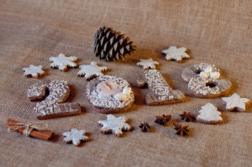 Holiday honey cookies stylized as wooden numbers 2, 0, 1, 8 and stars laying near pine cones, aniseed, cinnamon sticks