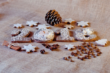 Fototapeta na wymiar New year holiday honey cookies in shape of numbers, stars laying on brown sackcloth background