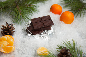 Fototapeta na wymiar chocolate bar with oranges on a snowy background
