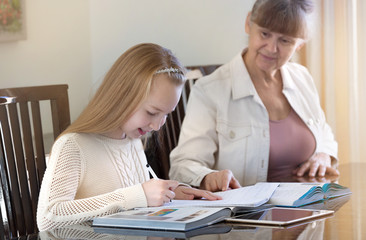 Fototapeta premium 10 years old girl and her teacher. Little girl study during her private lesson. Tutorial and educational concept.