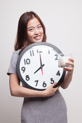Healthy Asian woman drinking  glass of milk hold clock.