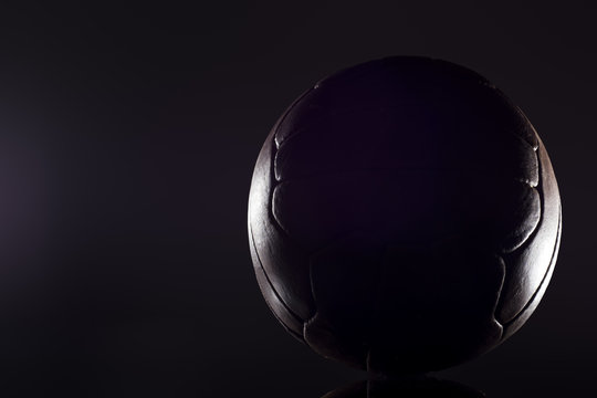 Old football leather ball on a black background
