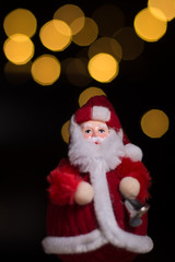 Santa Claus holding bell, Christmas theme, black background with bokeh lights, copy space
