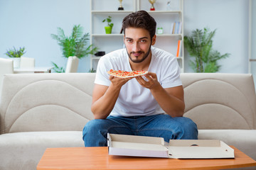 Man eating pizza having a takeaway at home relaxing resting