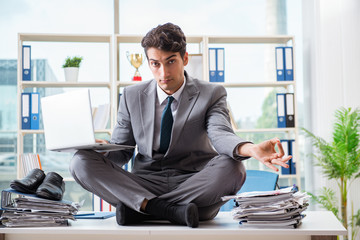 Businessman sitting on top of desk in office