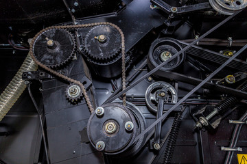 Mechanism of new modern agricultural combine harvester. Gears with chain drive, pulleys with drive belts. Industrial mechanical background