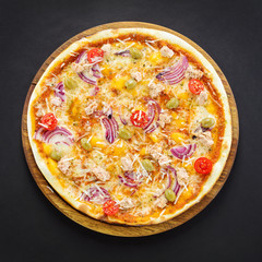 Delicious pizza on wooden board over black